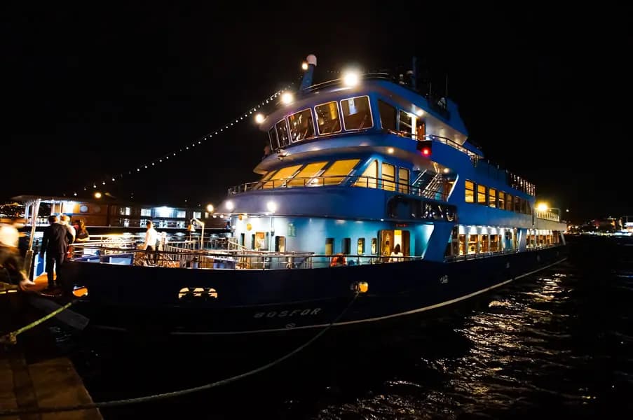 Guests boarding the BOSFOR at night, a mooring rope in the foreground
